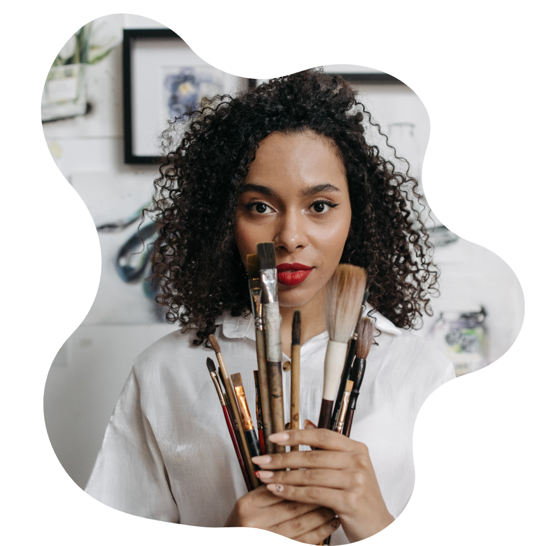 Woman holding paintbrushes with a blurred indoor background